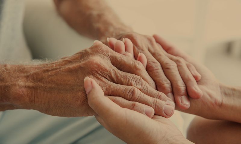 Ung och äldre person håller varandras händer